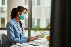 Woman at office desk with a PPE mask on
